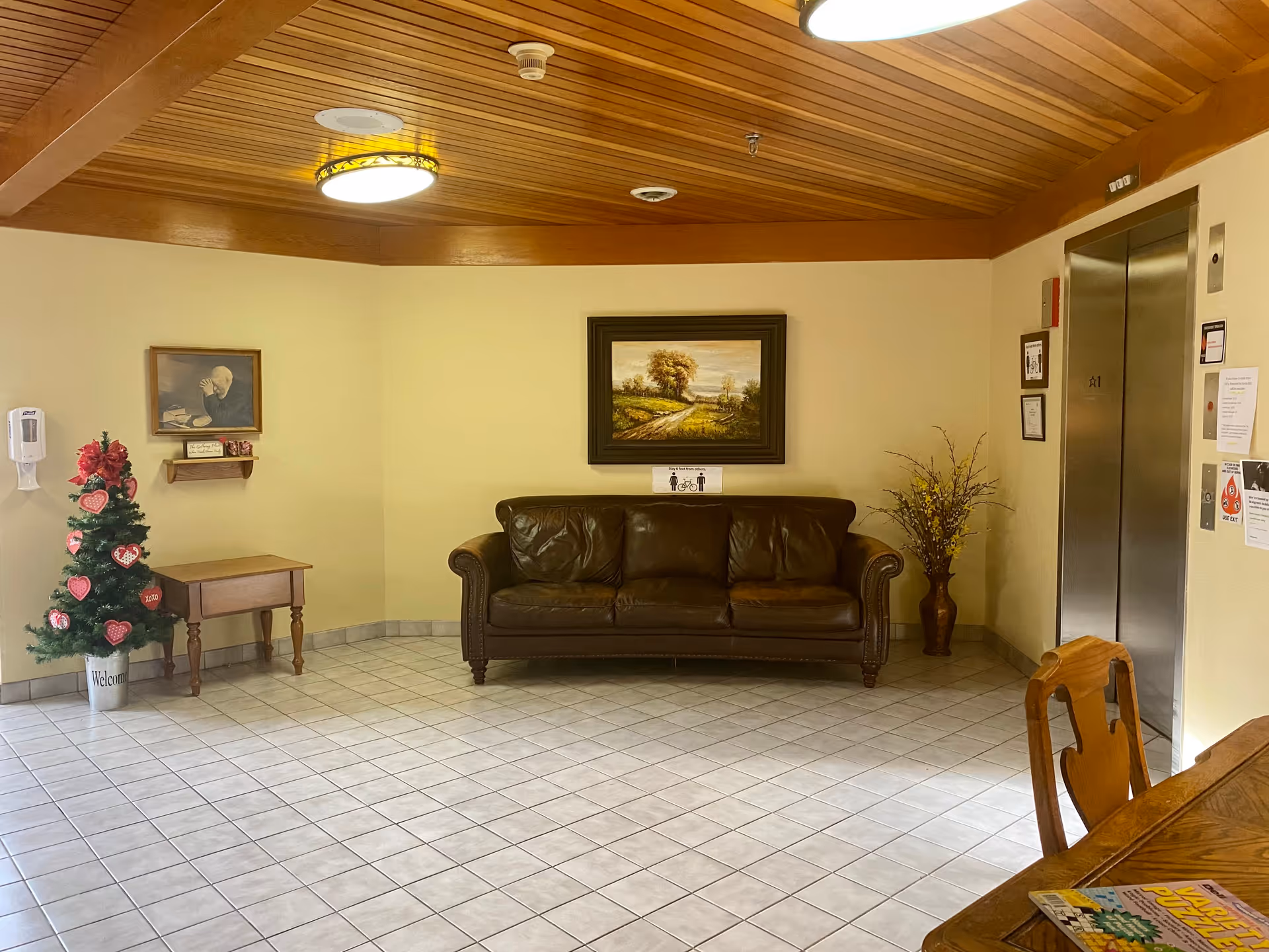 Carefree Living St.Cloud lobby with a leather sofa, art, Christmas tree, and elevator.