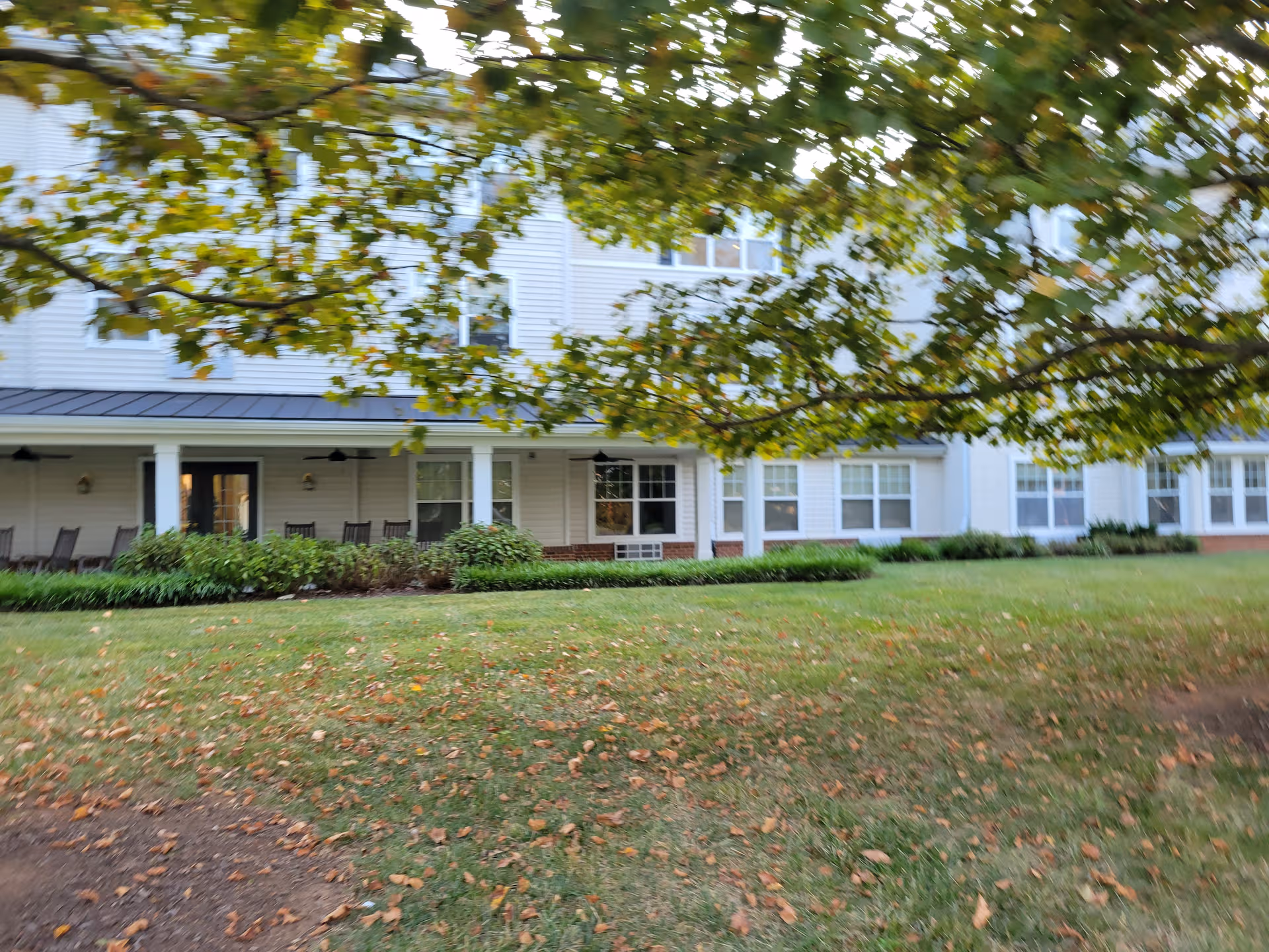 Front view of a white senior living building with a porch and green lawn.