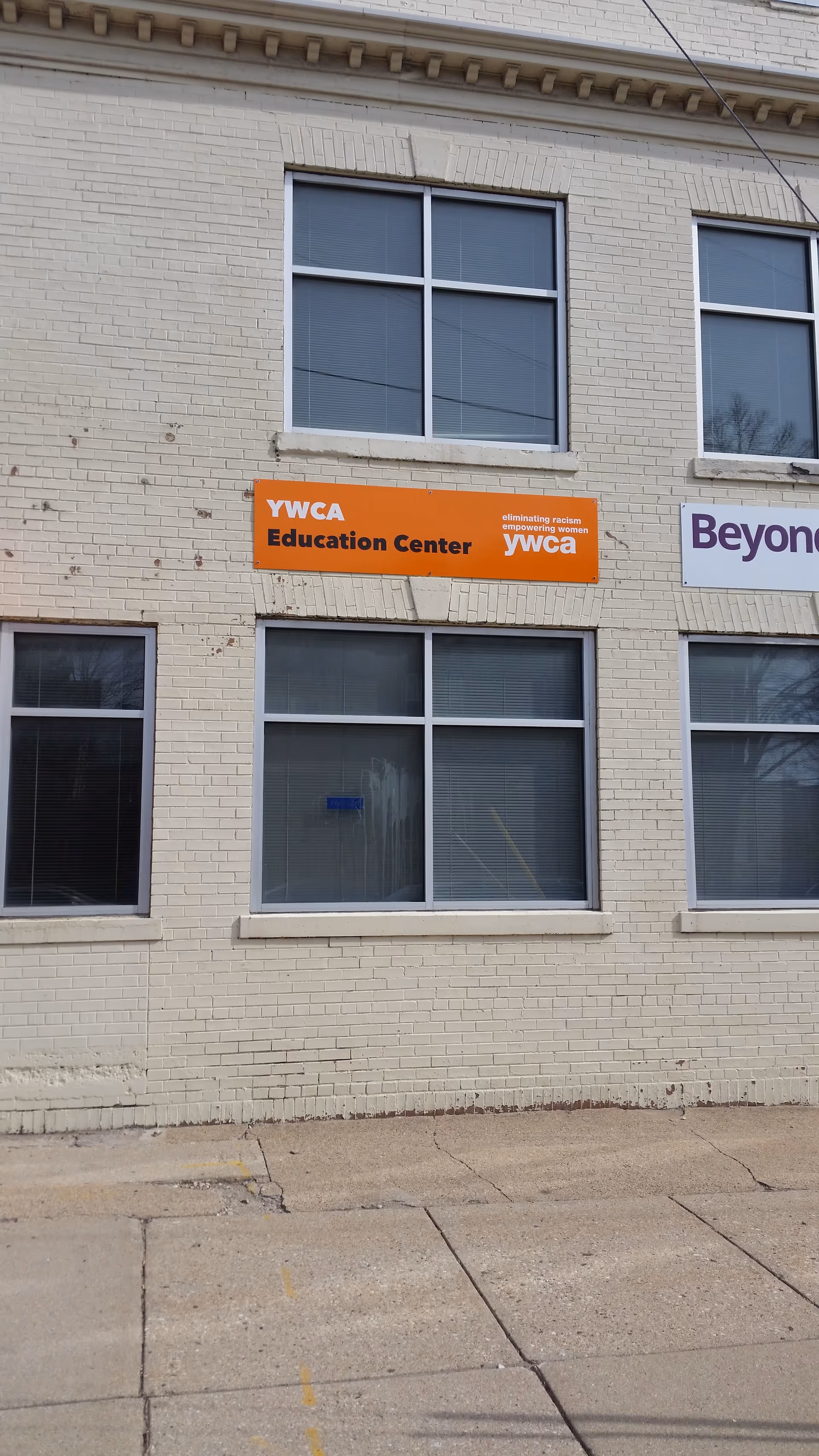 Exterior brick building with large windows and an orange YWCA Education Center sign.