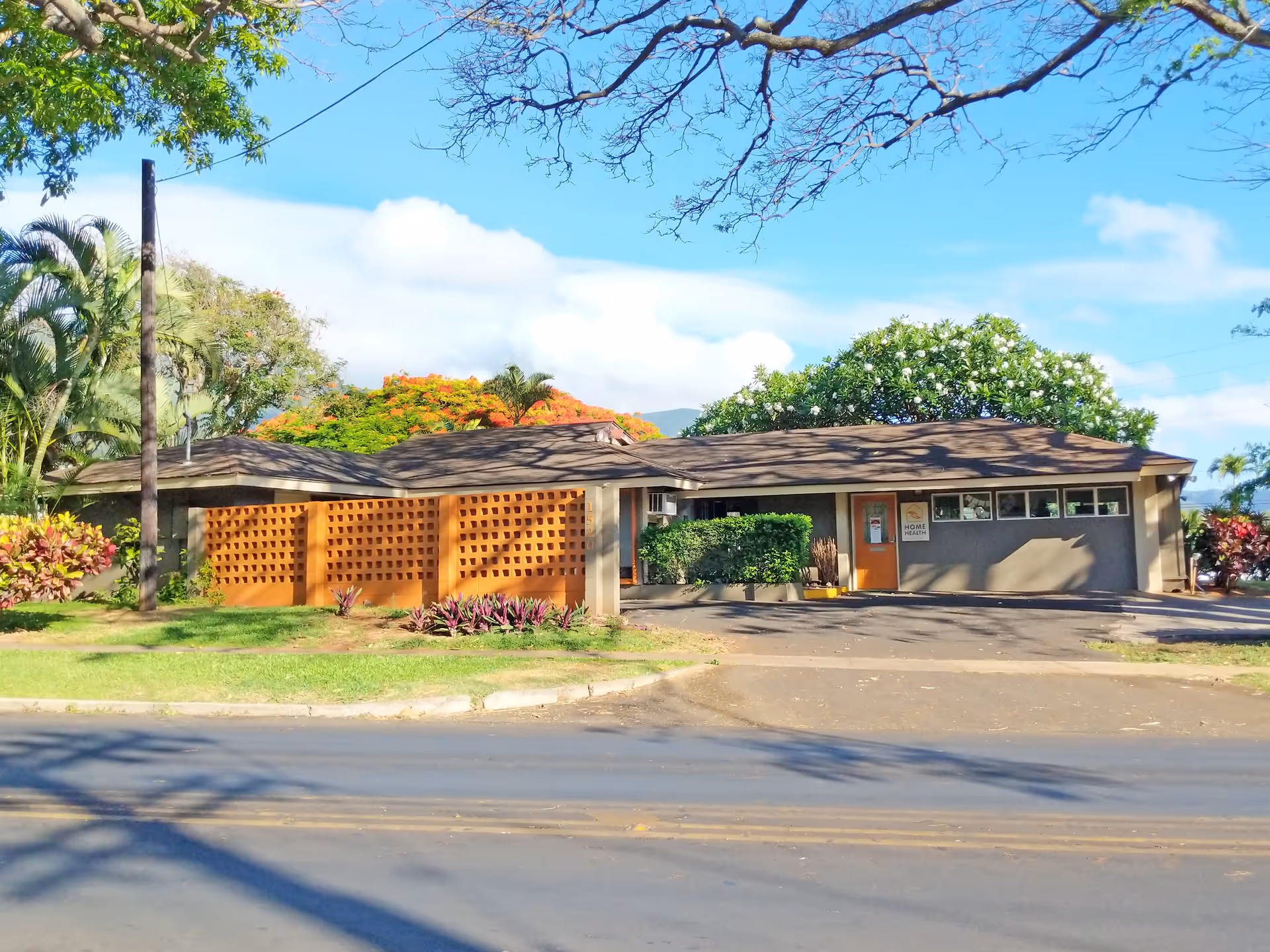 Single-story facility with lattice screens, a driveway, and tropical landscaping.