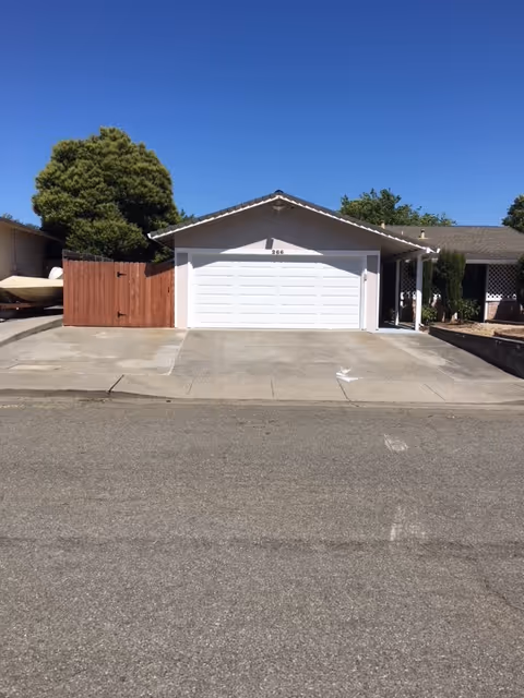 Front view of a single-story building with a white garage door and wide driveway.
