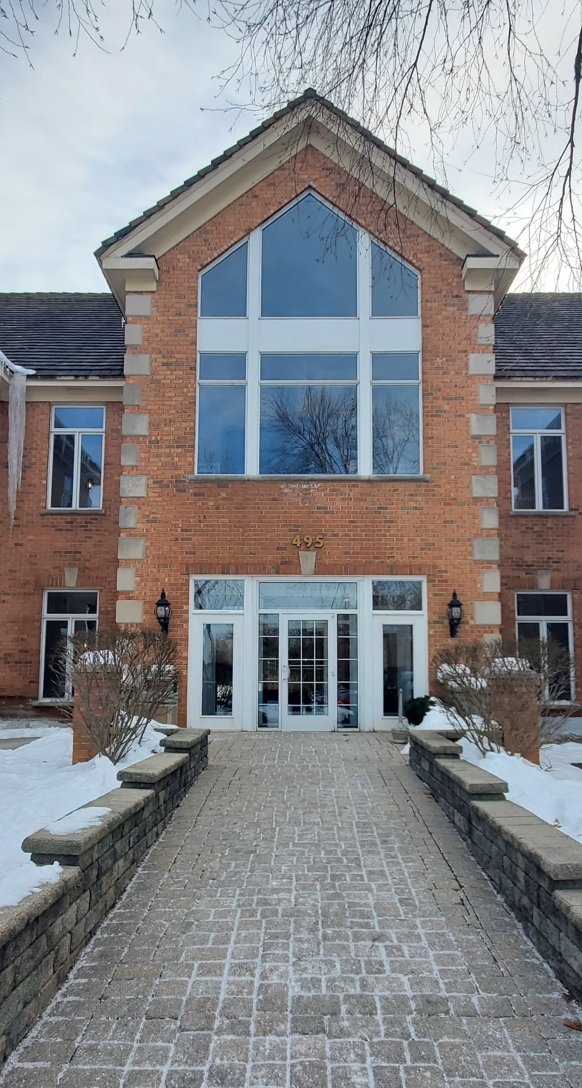 Brick building exterior with a central glass entrance and large front windows.