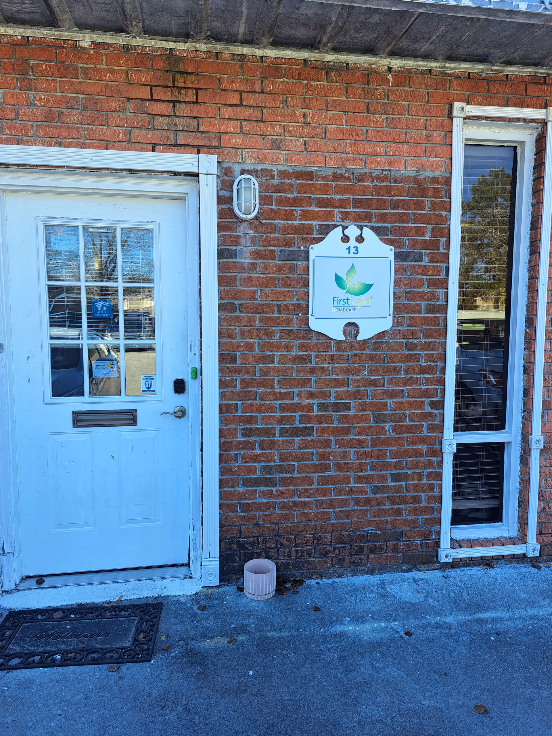 Exterior brick building entrance with white door and FirstLight Home Care sign.
