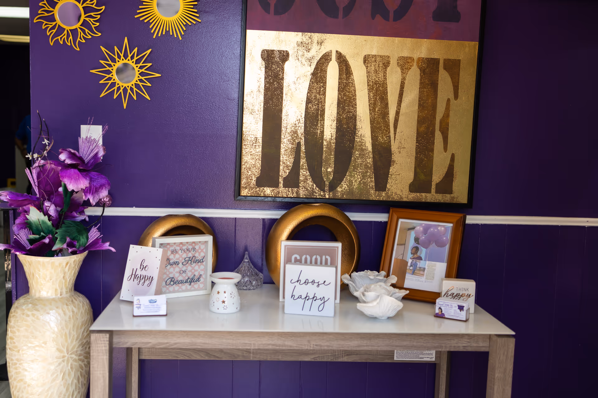 Purple wall with a large LOVE sign and decorative items arranged on a table.