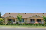 Arbor Faire Senior Apartments front exterior with landscaped lawn and trees.