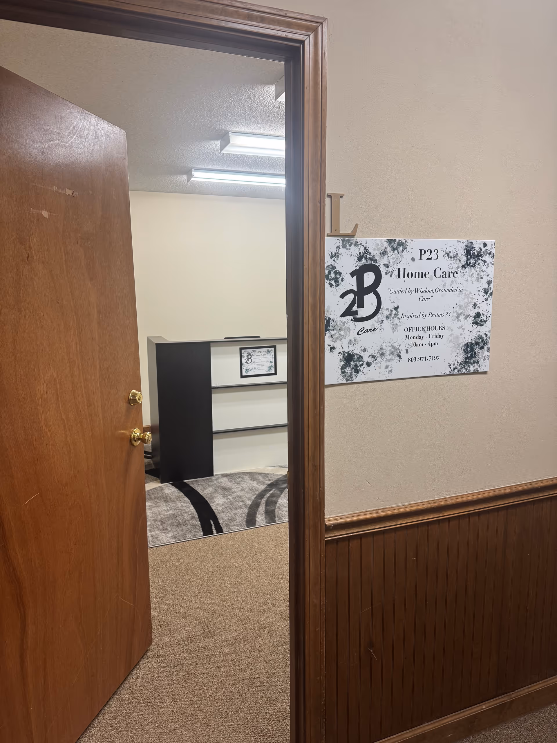 Open wooden door leads to a hallway with a P23 Home Care sign on the wall.