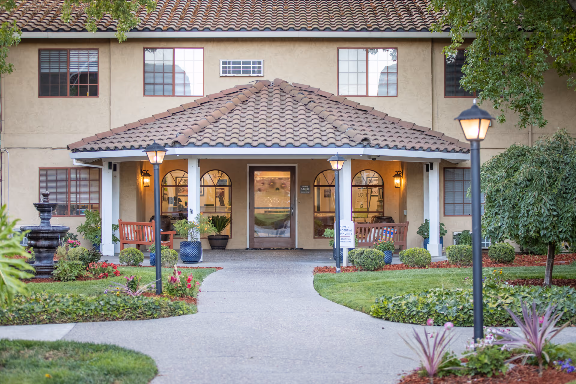 Exterior view of Cogir of Manteca entrance with benches, path, and landscaping.