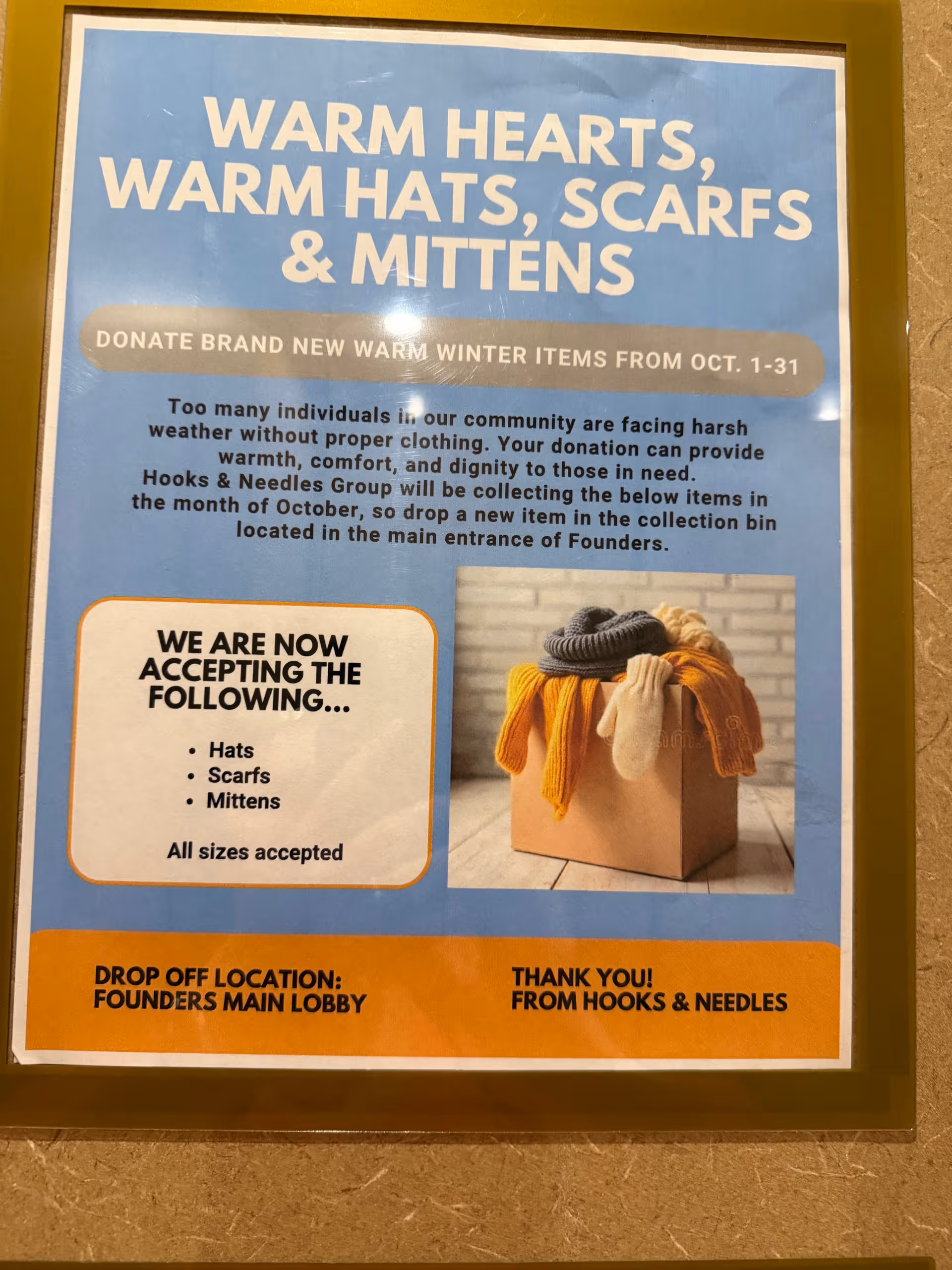 Blue donation poster about warm hats, scarves, and mittens in a facility hallway.