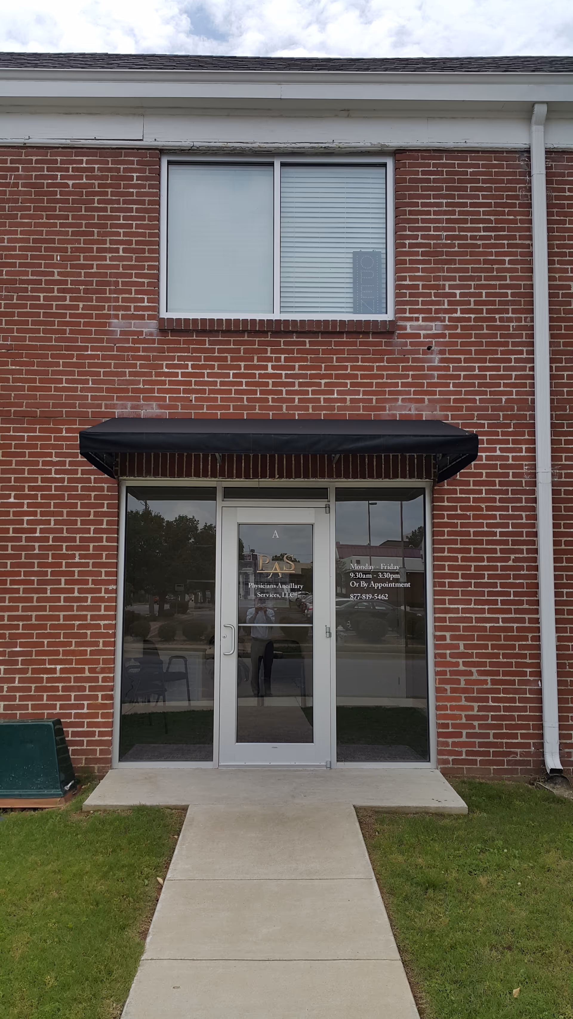 Brick facility exterior with glass entrance doors displaying Physicians Ancillary Services, LLC, and a black awning.