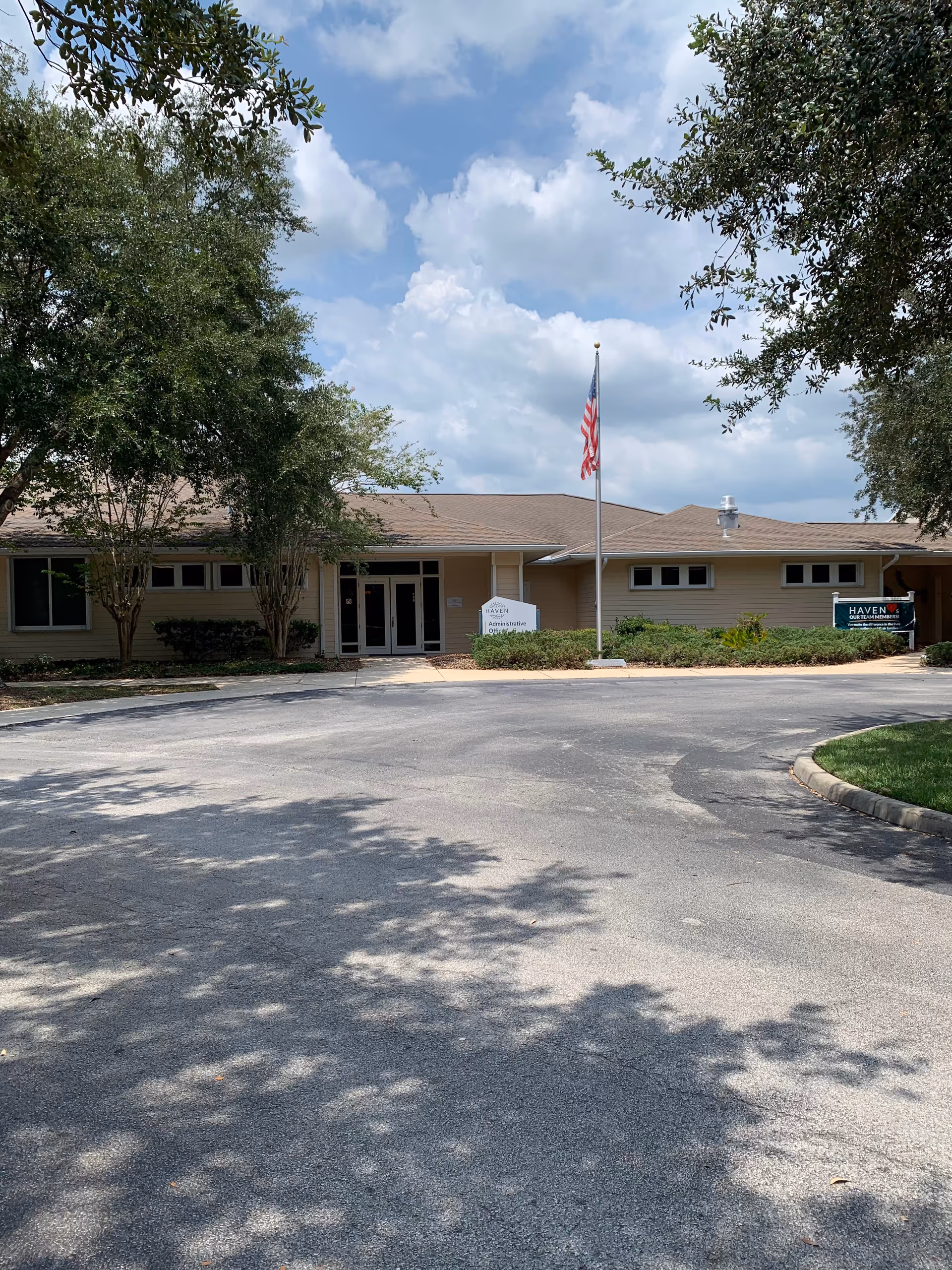 Exterior view of Haven Roberts Hospice Care Center with entrance, flagpole, and trees.