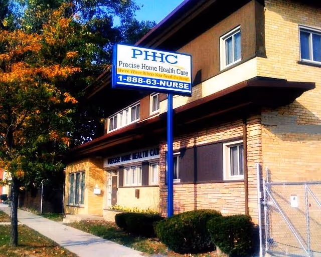 Two-story brick building exterior with a blue PHC sign on a tall pole in front.
