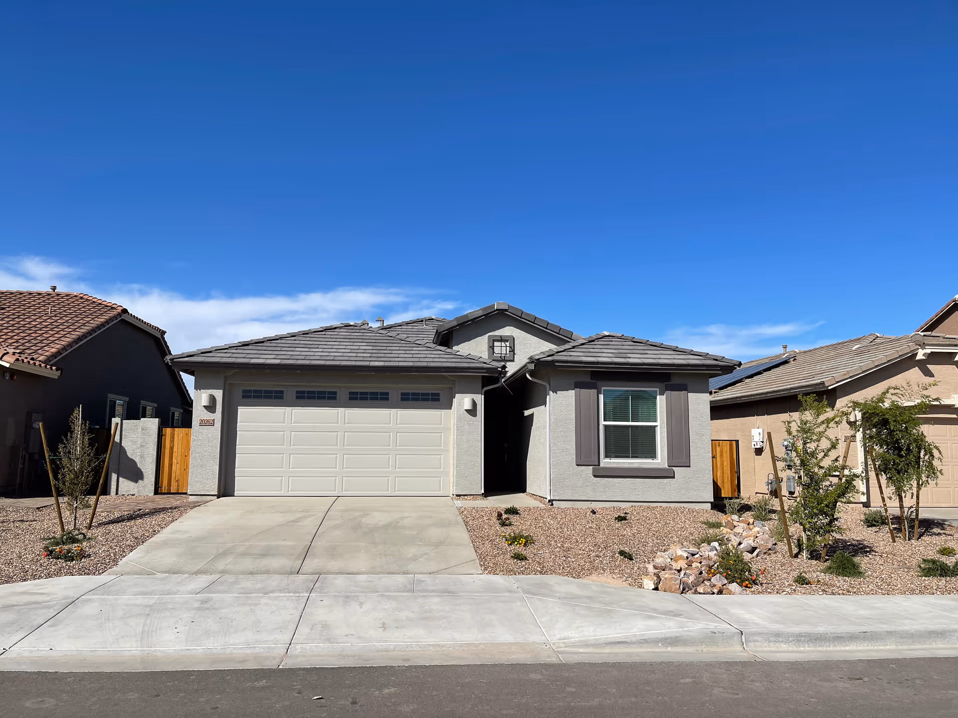 Front exterior of a single-story gray building with a two-car garage and desert landscaping.