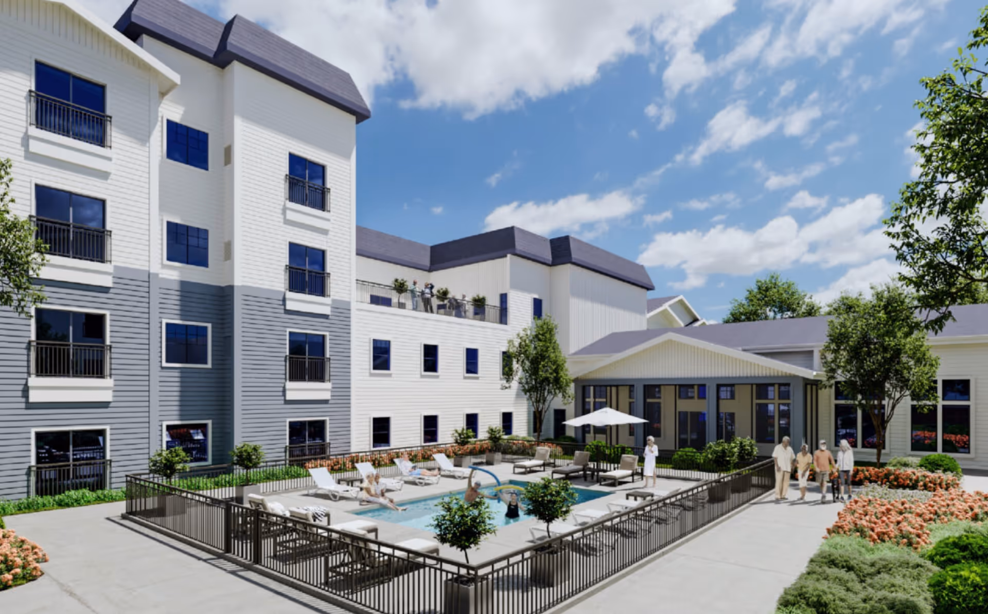 Outdoor courtyard area of a senior living facility with a fenced swimming pool surrounded by lounge chairs and small trees. Several elderly people are enjoying the pool and walking nearby. The building is white with gray accents and multiple windows, under a partly cloudy blue sky.