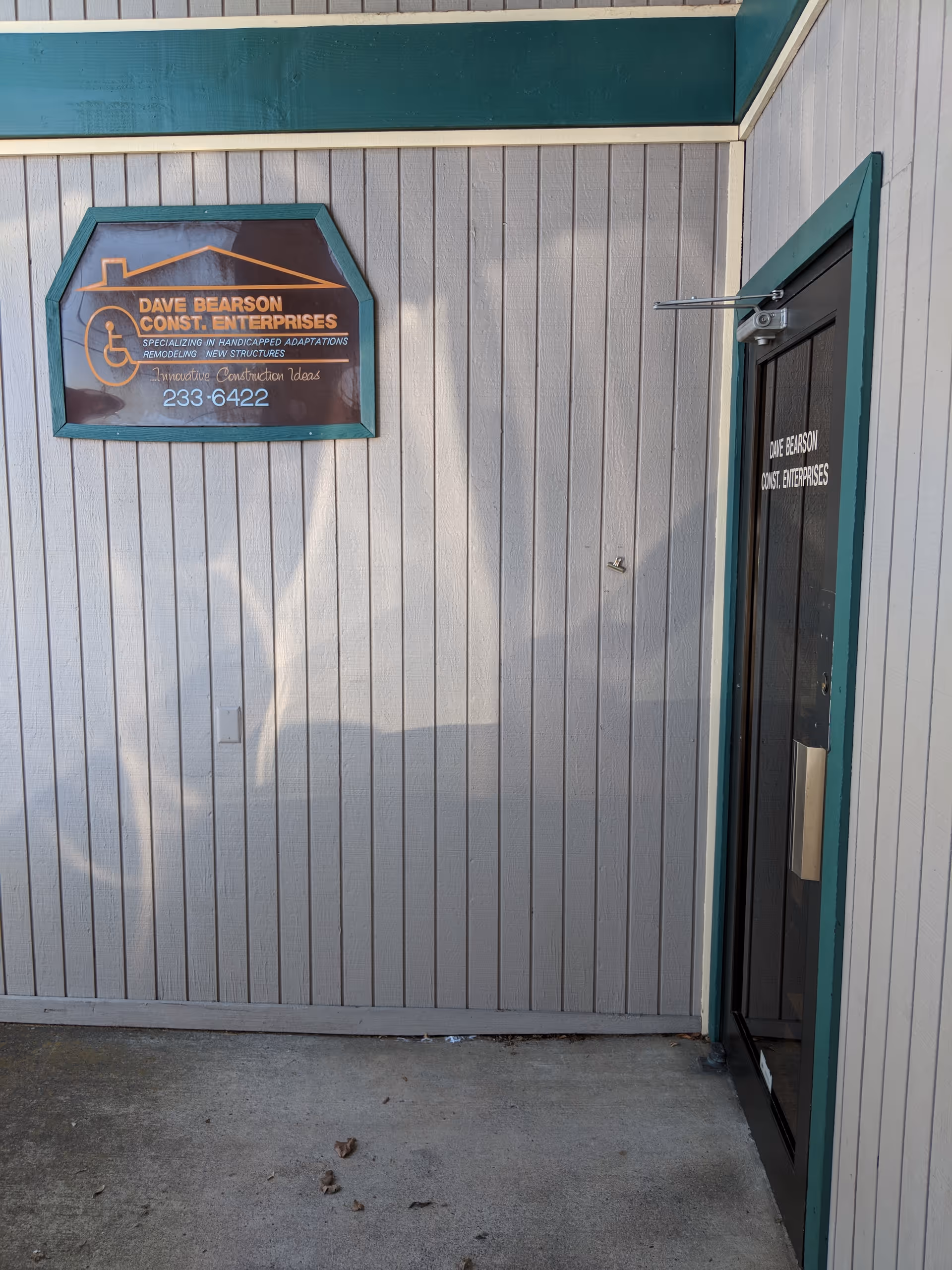Exterior wall with teal-trimmed door and a Bearson Enterprises sign.