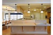 Open kitchen with island, pendant lights, and dining area in a senior living facility.
