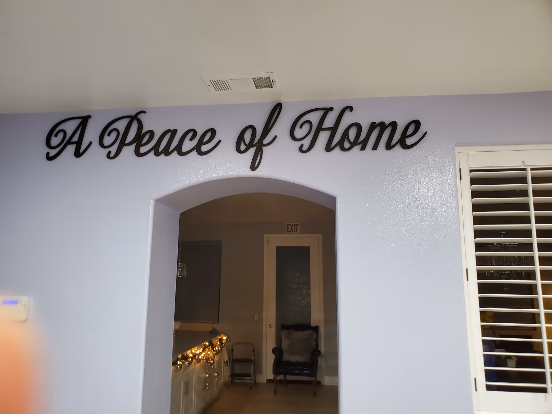 Interior lobby with arch doorway and lavender wall sign reading A Peace of Home.
