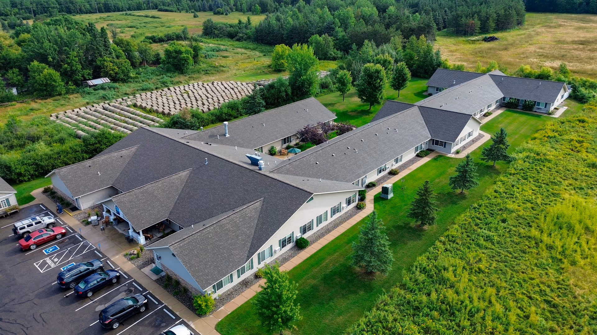 Aerial view of a single-story senior living campus with interconnected wings and surrounding green grounds.
