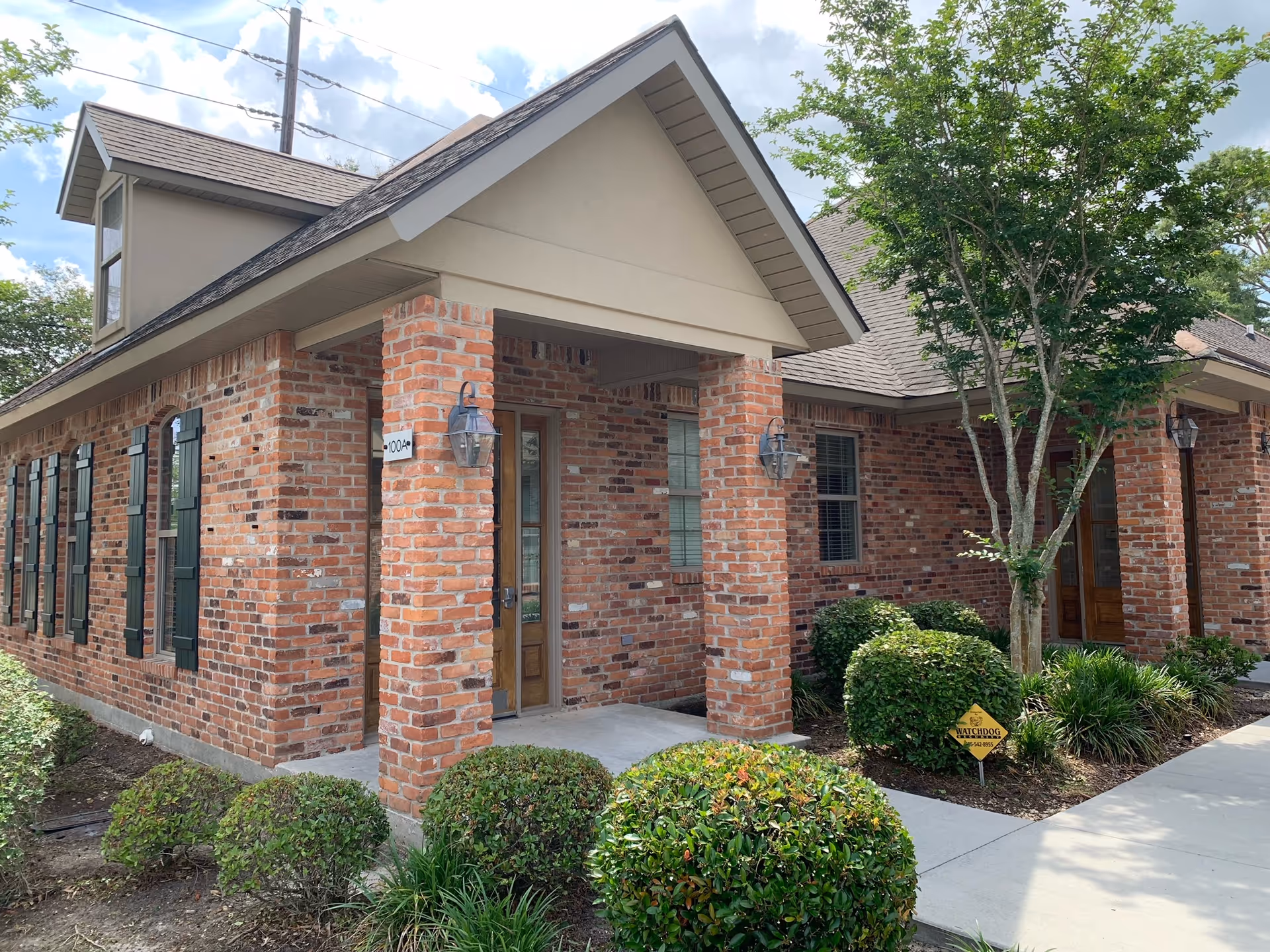 Red brick senior living facility exterior with covered entrance and landscaped shrubs