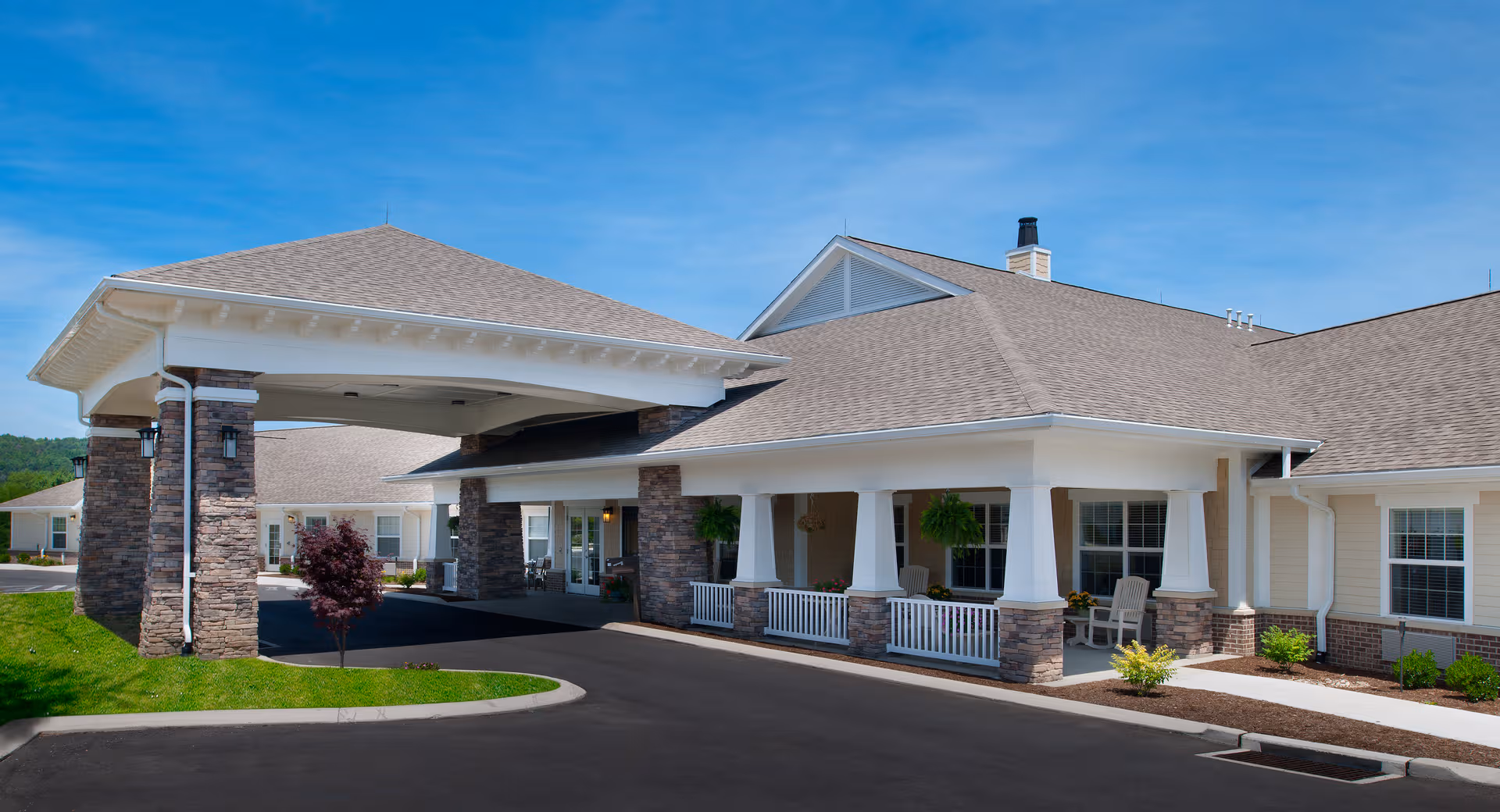 Front view of a senior living facility with a covered entrance and stone columns.