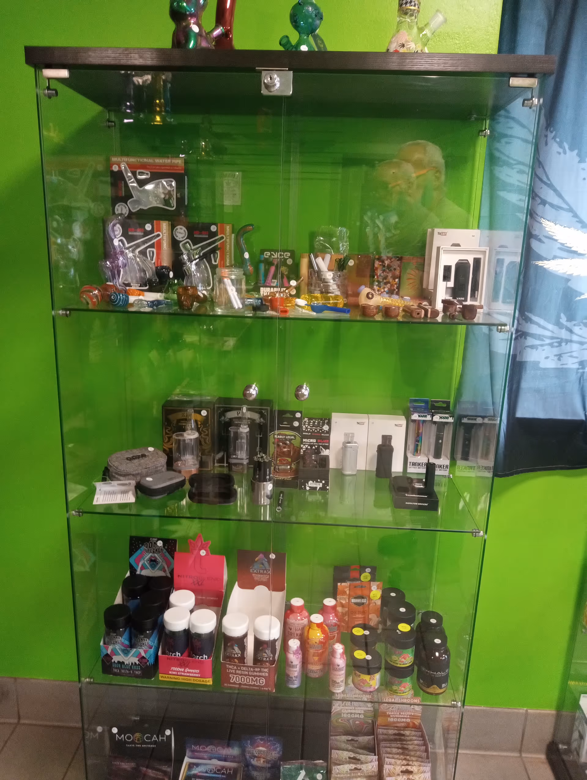 Bright green wall behind a glass display cabinet filled with assorted products.