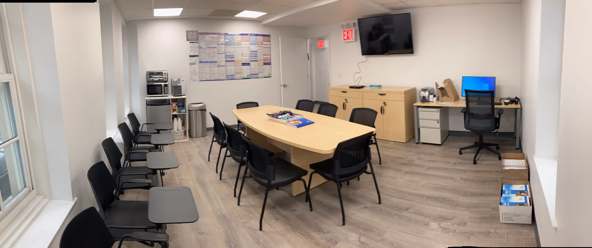 Empty conference room with a long table, chairs, and wall-mounted TV in Attending Home Care Queens.