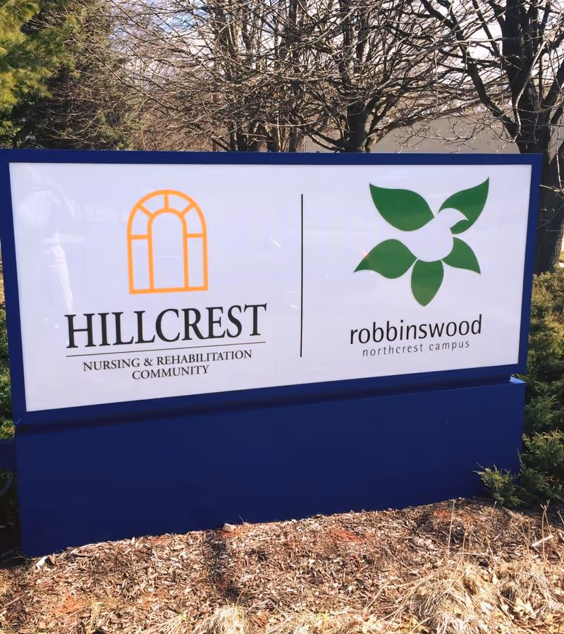 Outdoor freestanding sign displaying the Hillcrest Nursing & Rehabilitation Community logo and the robbinswood northcrest campus logo.