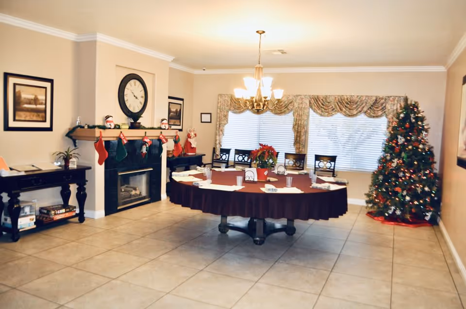 A festive dining room in a senior living facility with a round table and Christmas tree.