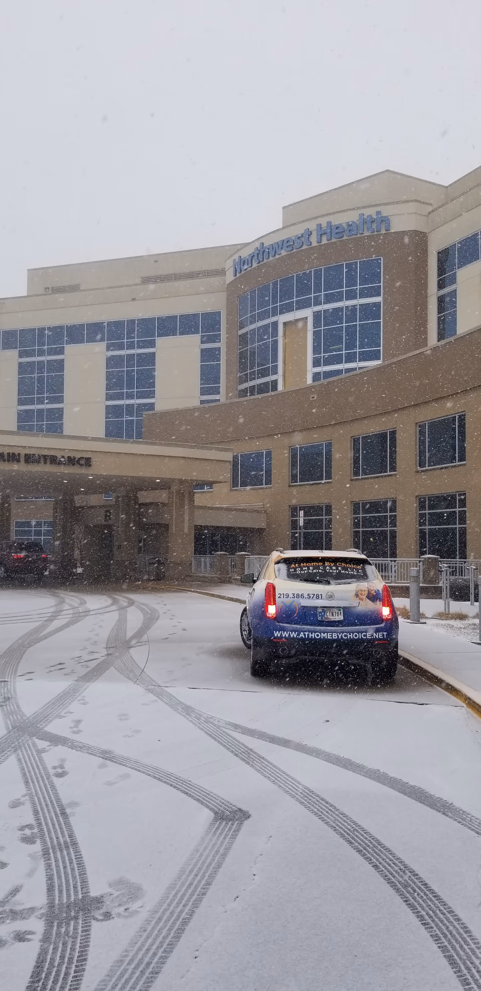 Snowy exterior of a care facility with a branded car near the main entrance.