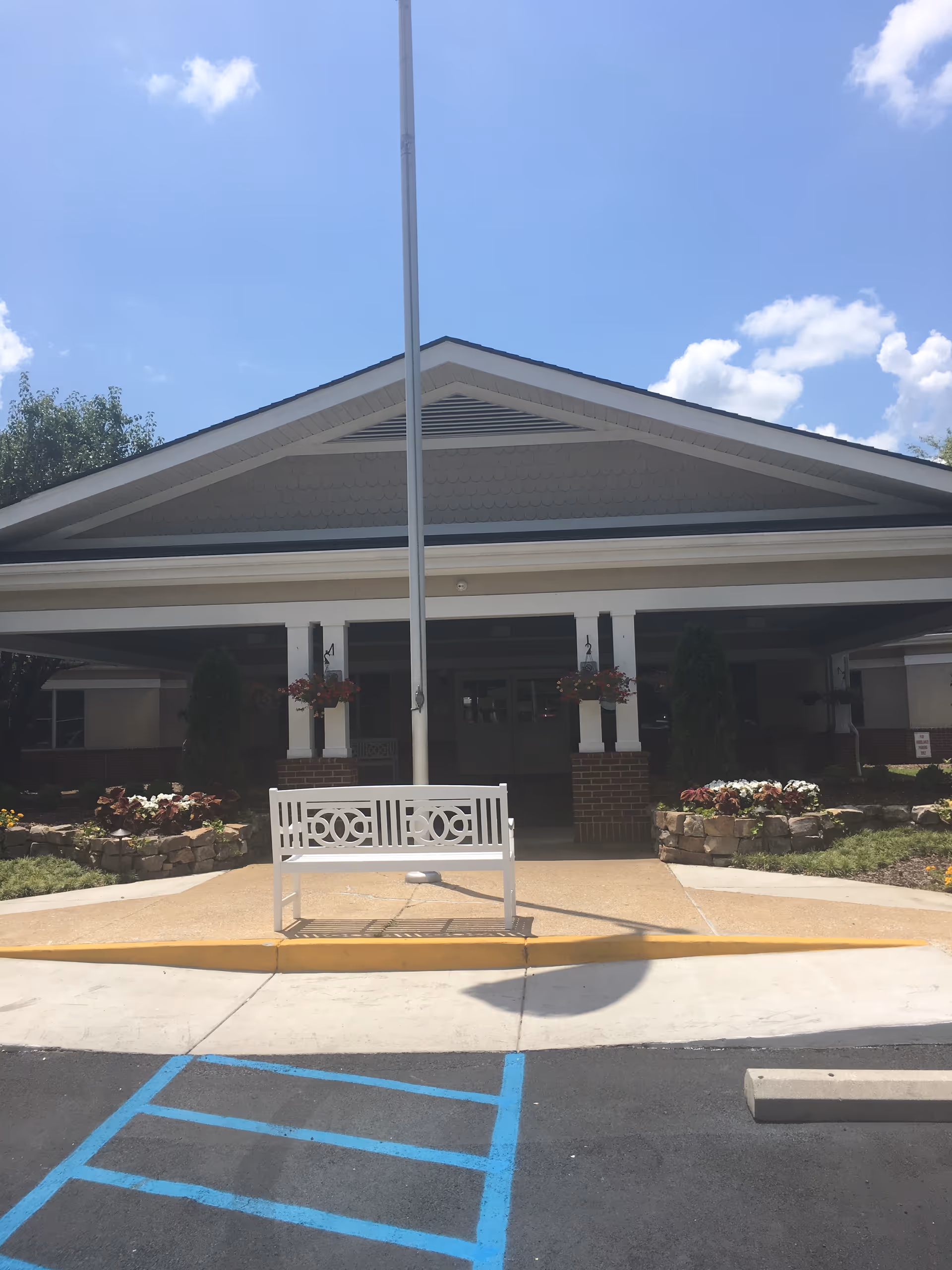 Exterior view of The Center for Advanced Rehab at Parkside entrance with a bench.
