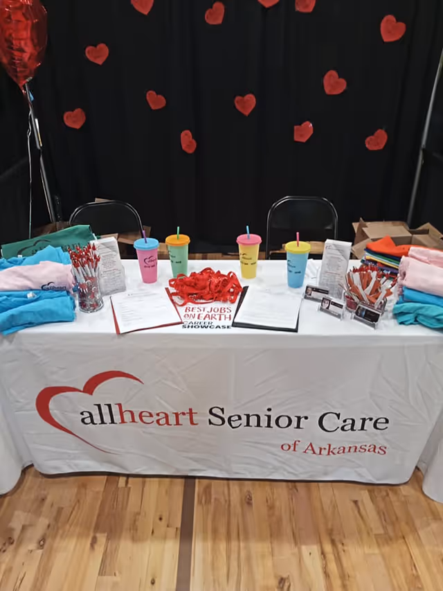 Promotional booth table for Allheart Senior Care with heart decorations indoors.