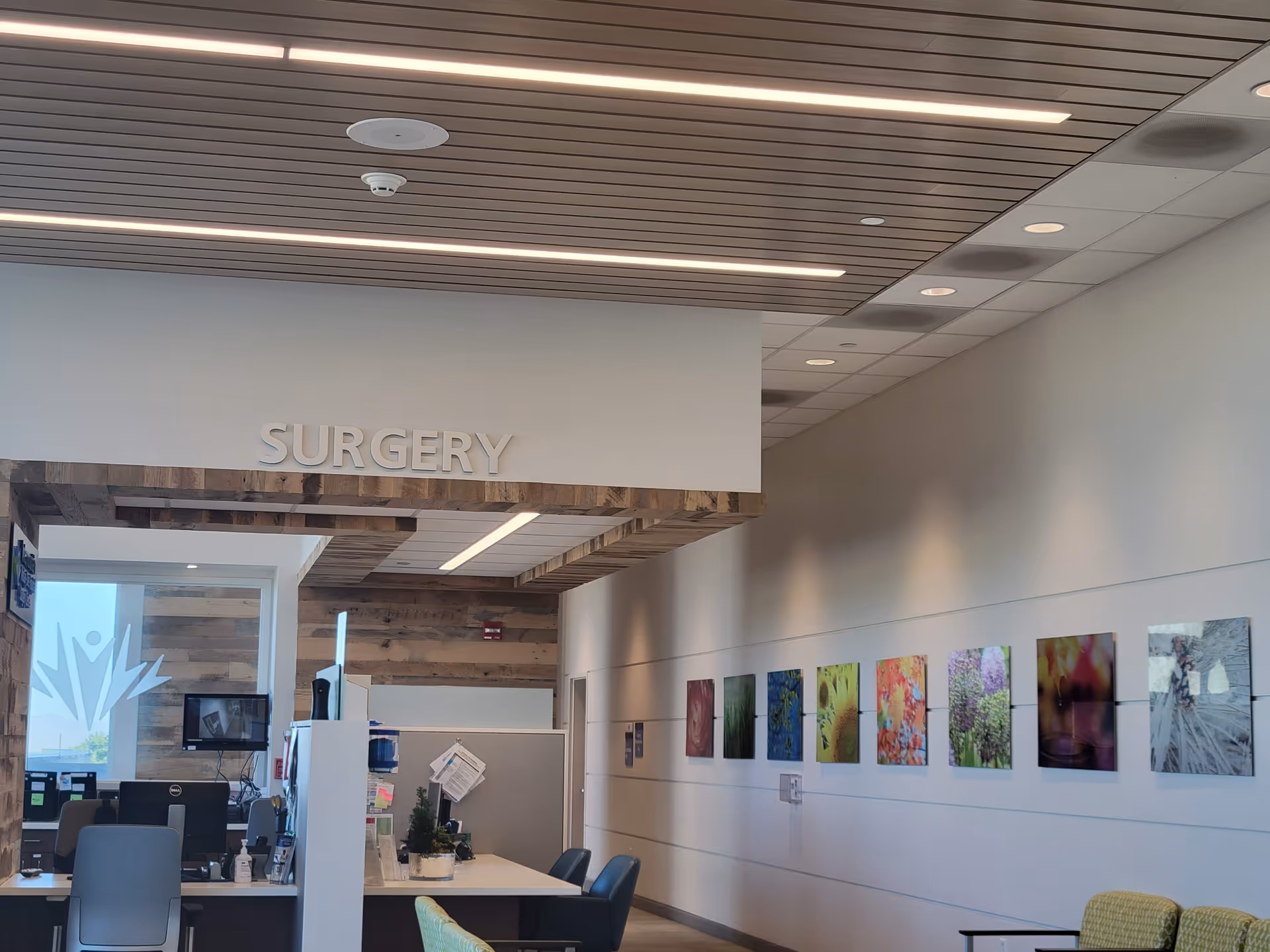 Modern reception area labeled SURGERY with desks, chairs, and colorful wall art.