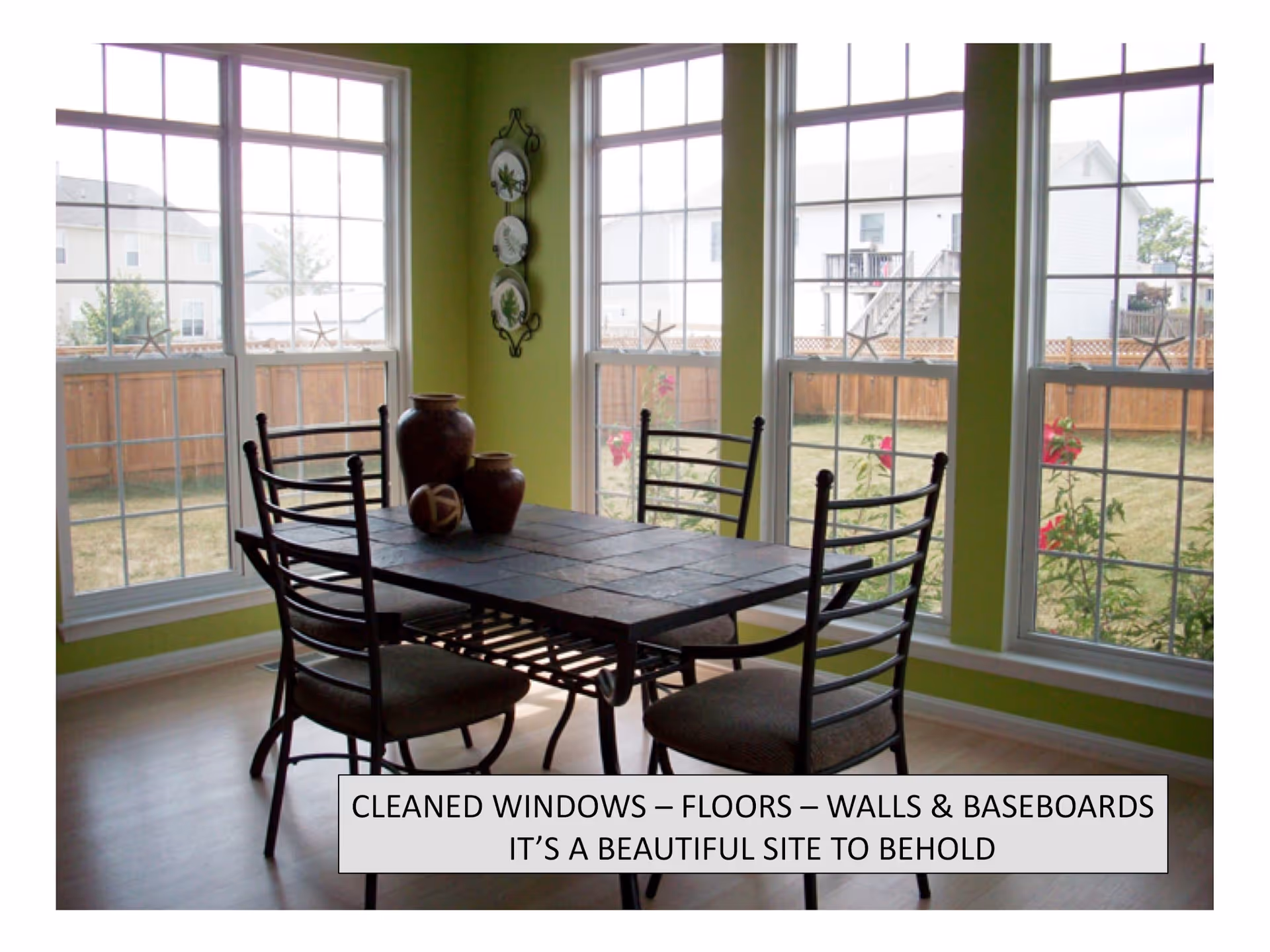 Bright dining area with a square table and metal chairs beside large windows.