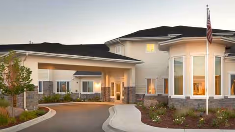 Front exterior view of a modern senior living facility with curved walkway and entrance.