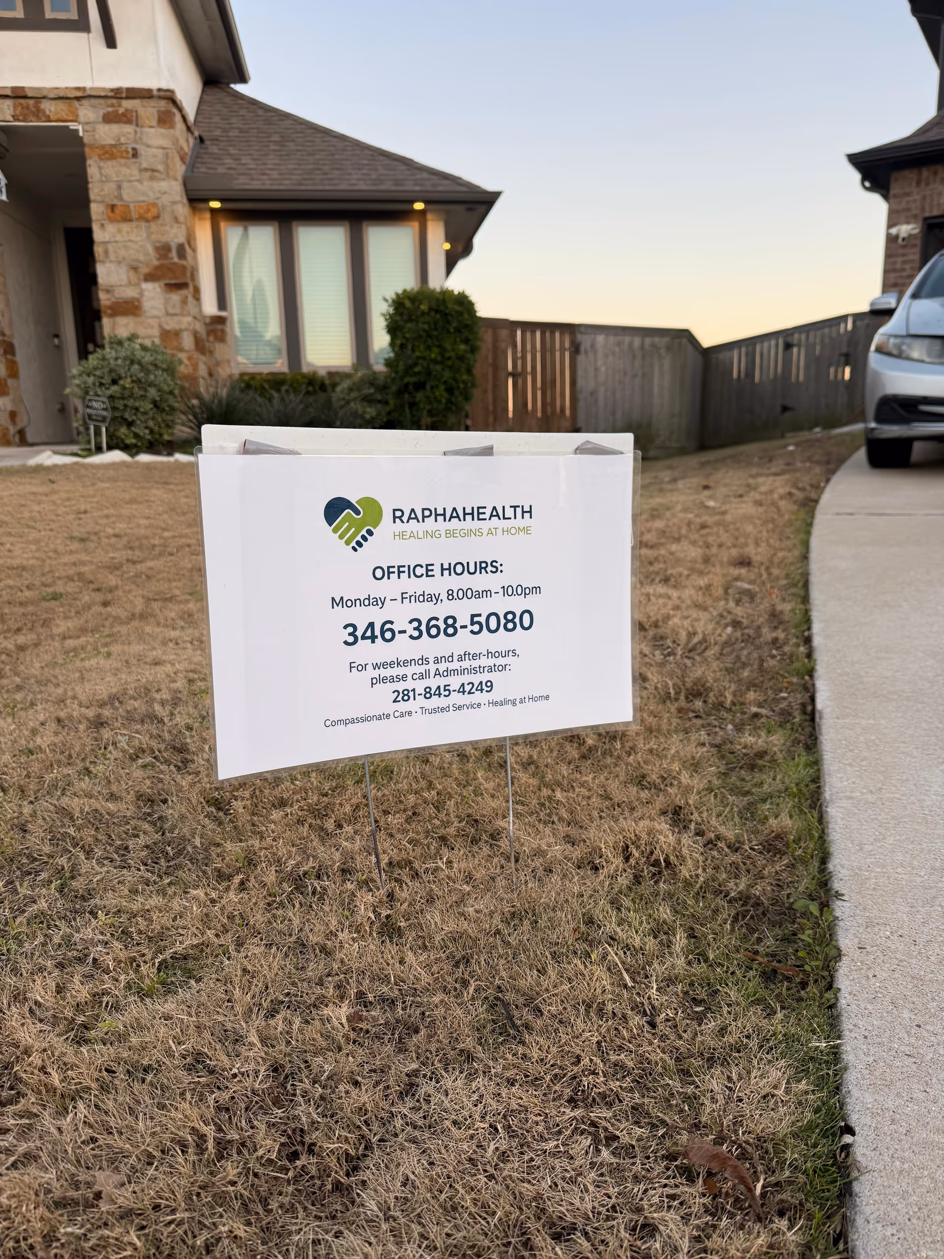 Sign advertising Rapha Health office hours on a lawn in front of a house exterior.