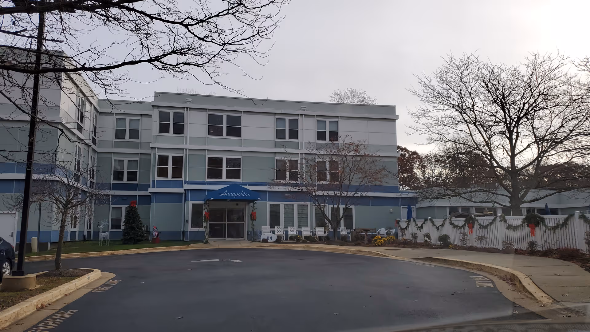 Exterior view of Annapolitan Care Center with the front entrance, circular driveway, and trees.