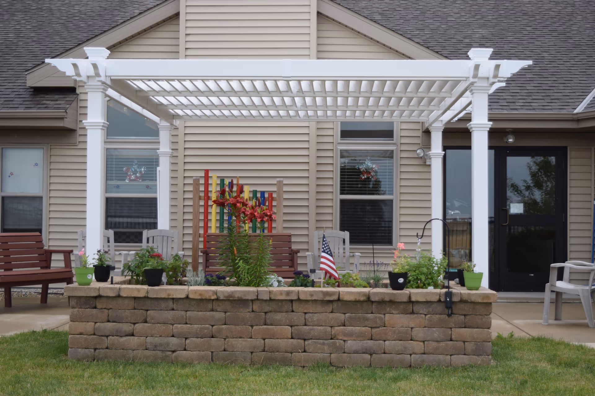 Exterior view of Spero Heritage Homes with a white pergola, patio seating, and stone planters.
