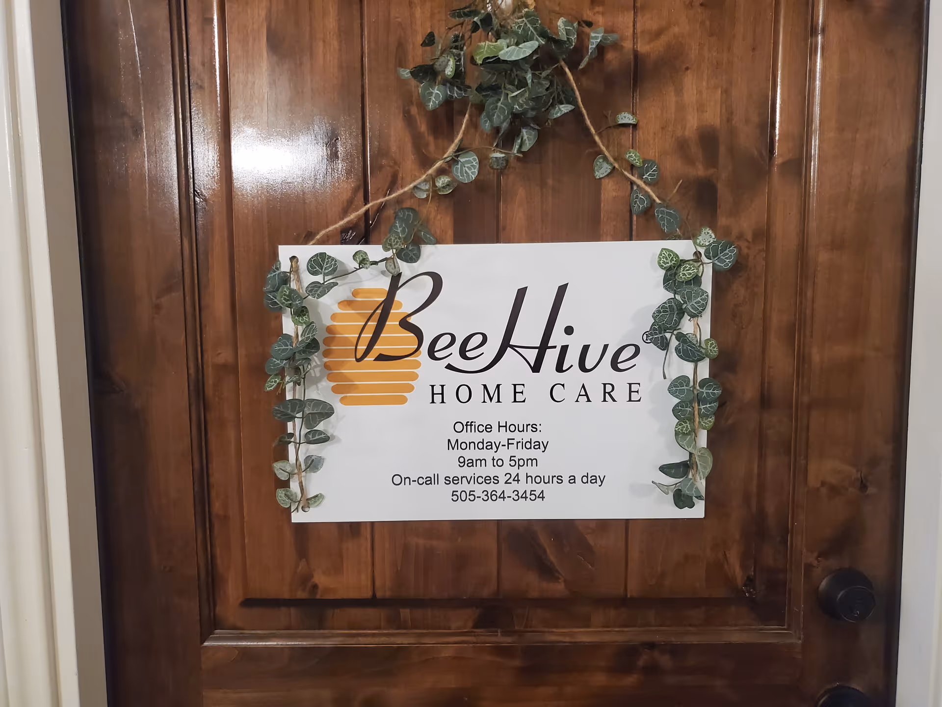 Wooden door with BeeHive Home Care sign framed by decorative vines