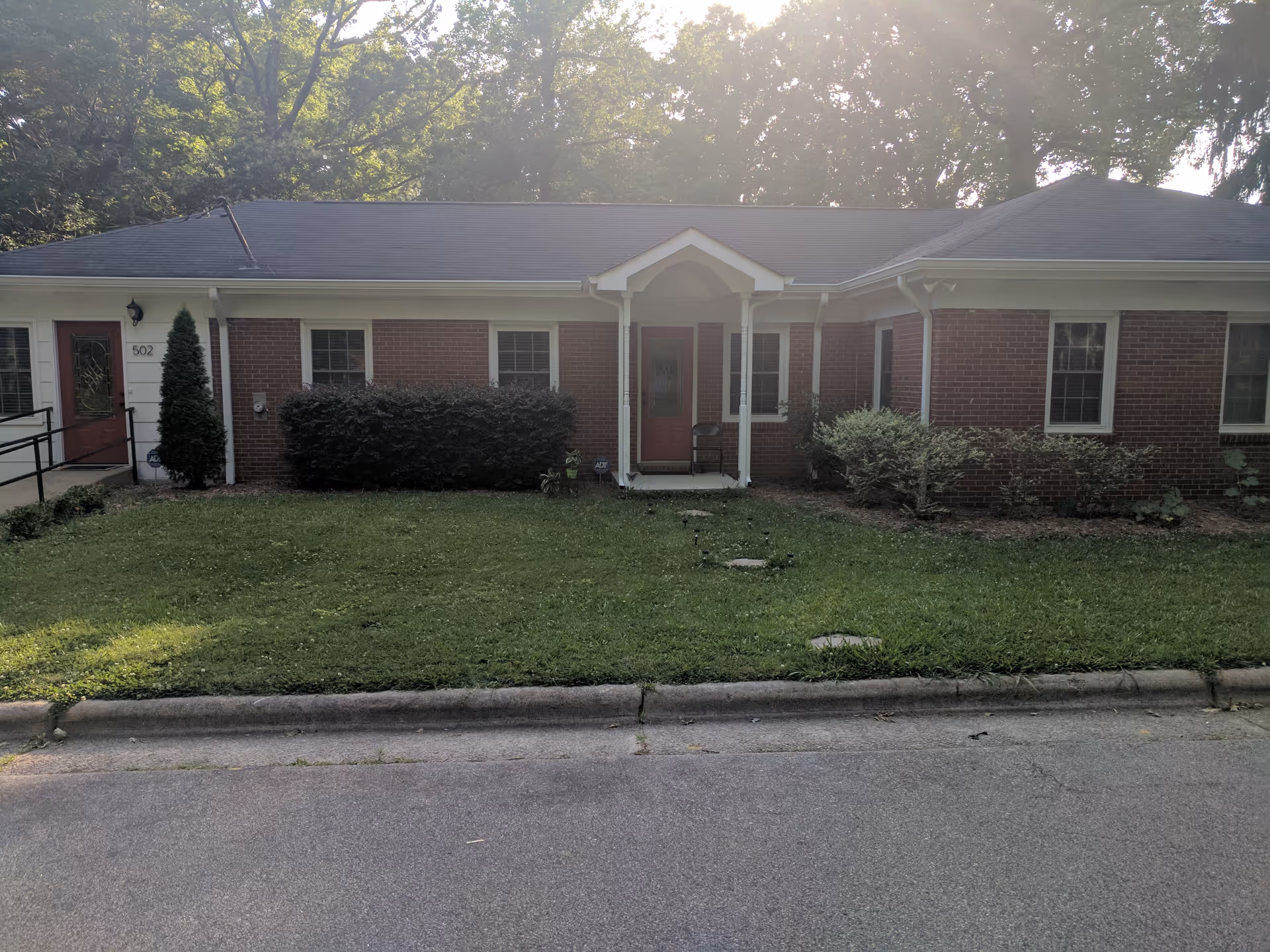 Single-story brick facility with small front porch, manicured lawn, and shrubs along entrance.