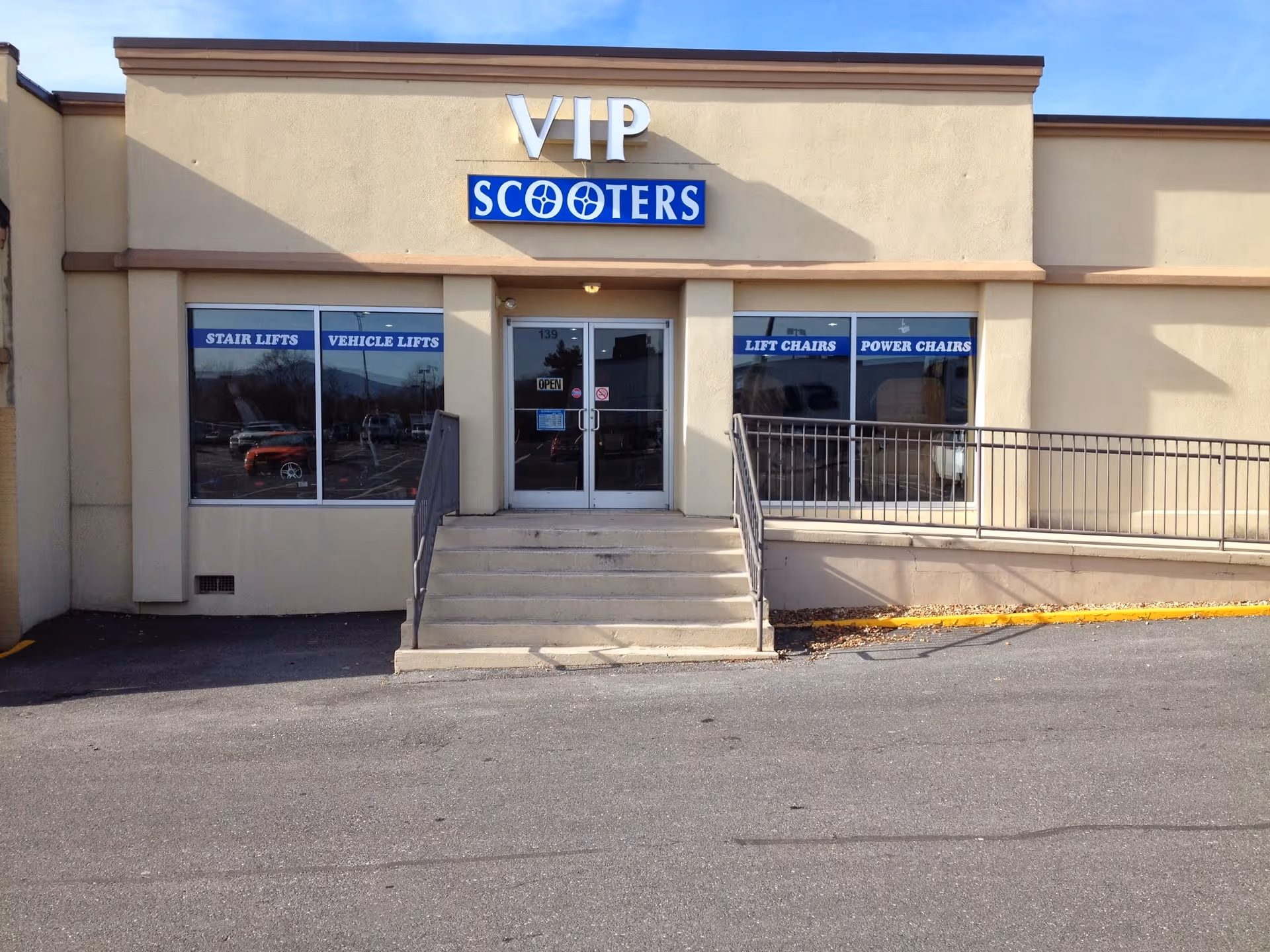 Front of a beige building labeled VIP Scooters with stairs and glass doors