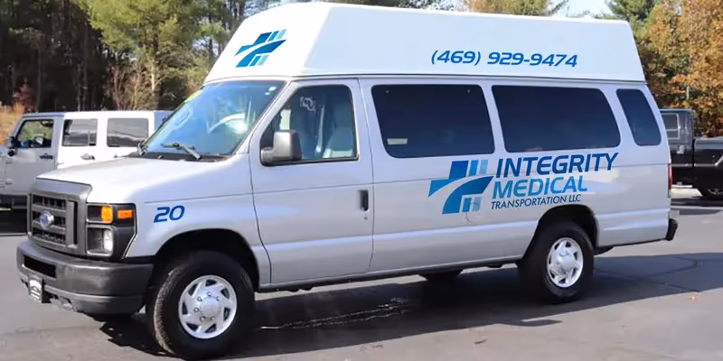 White van with Integrity Medical Transportation branding parked in a lot, side windows visible.