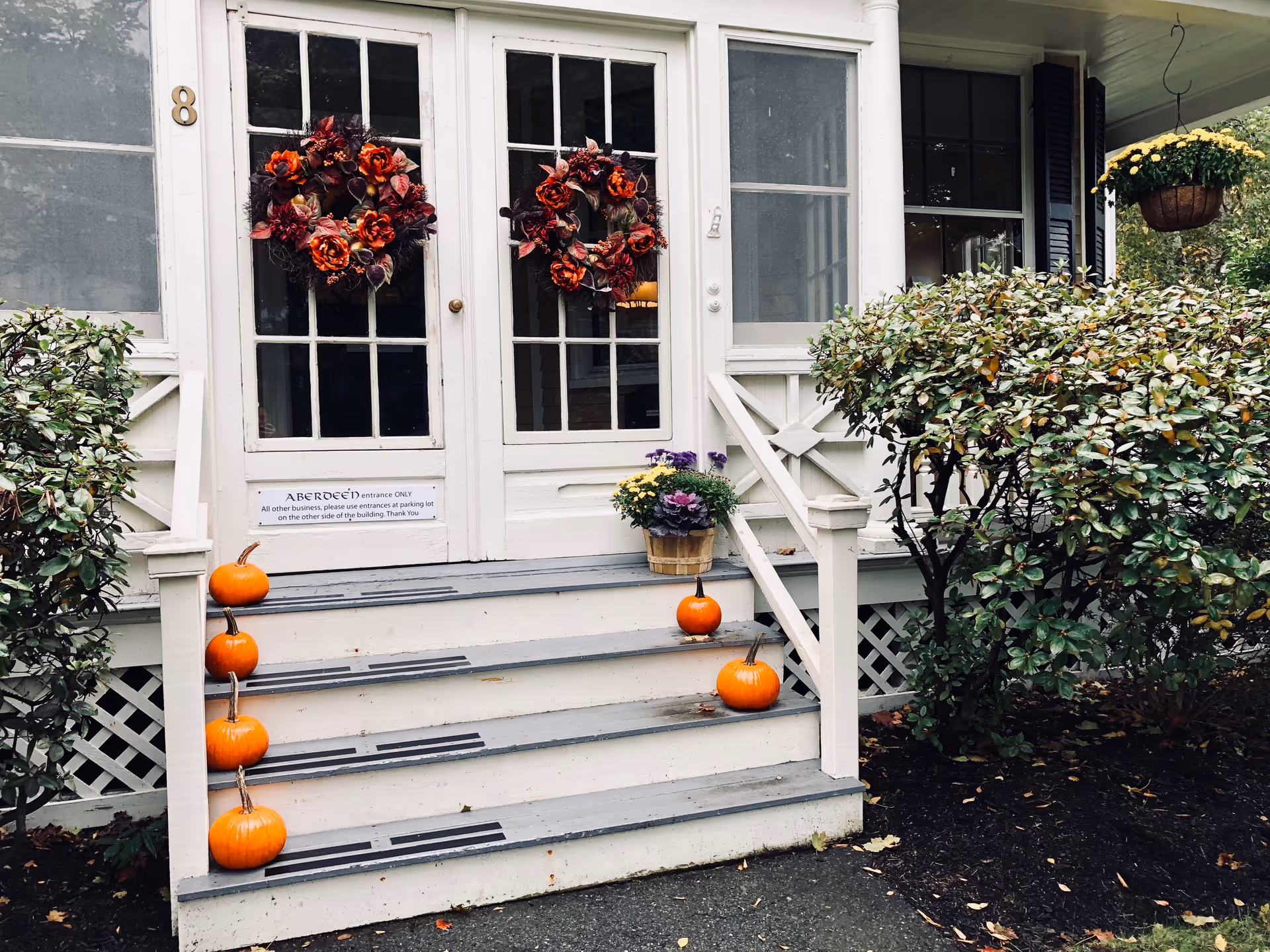 White front porch with pumpkins, wreaths, and potted plants at Aberdeen Home Care.