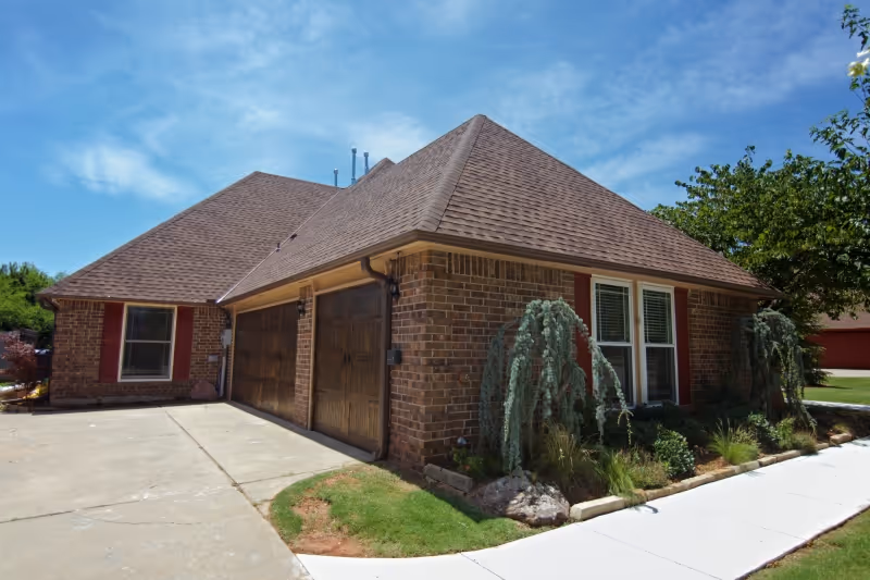 Brick, single-story house with a two-car garage and landscaped front yard.