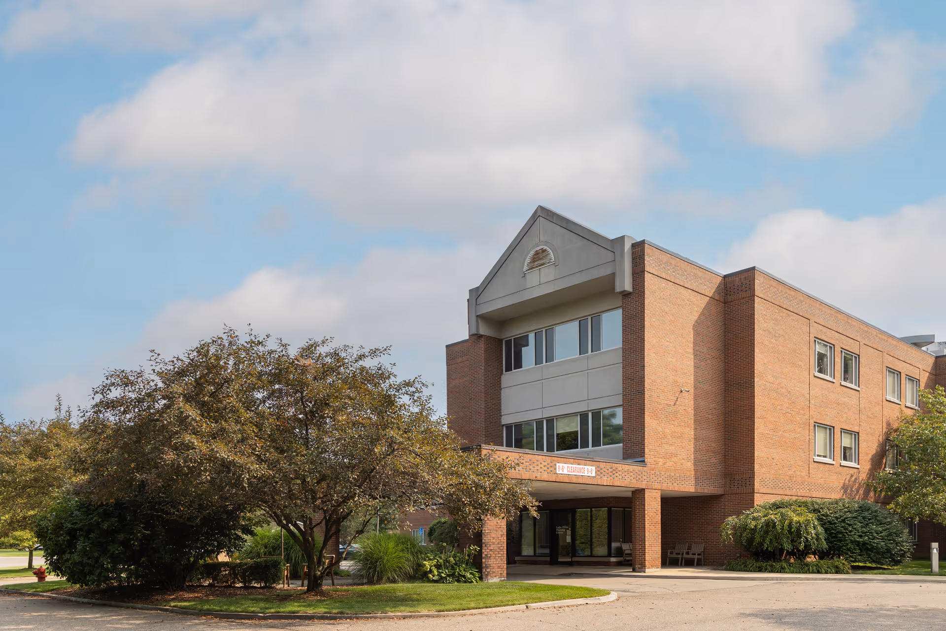 Lake Orion Nursing Center exterior with trees, entrance, and a covered drop-off area.