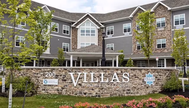 Front exterior of Villas of Holmdel senior living with stone sign and entrance.