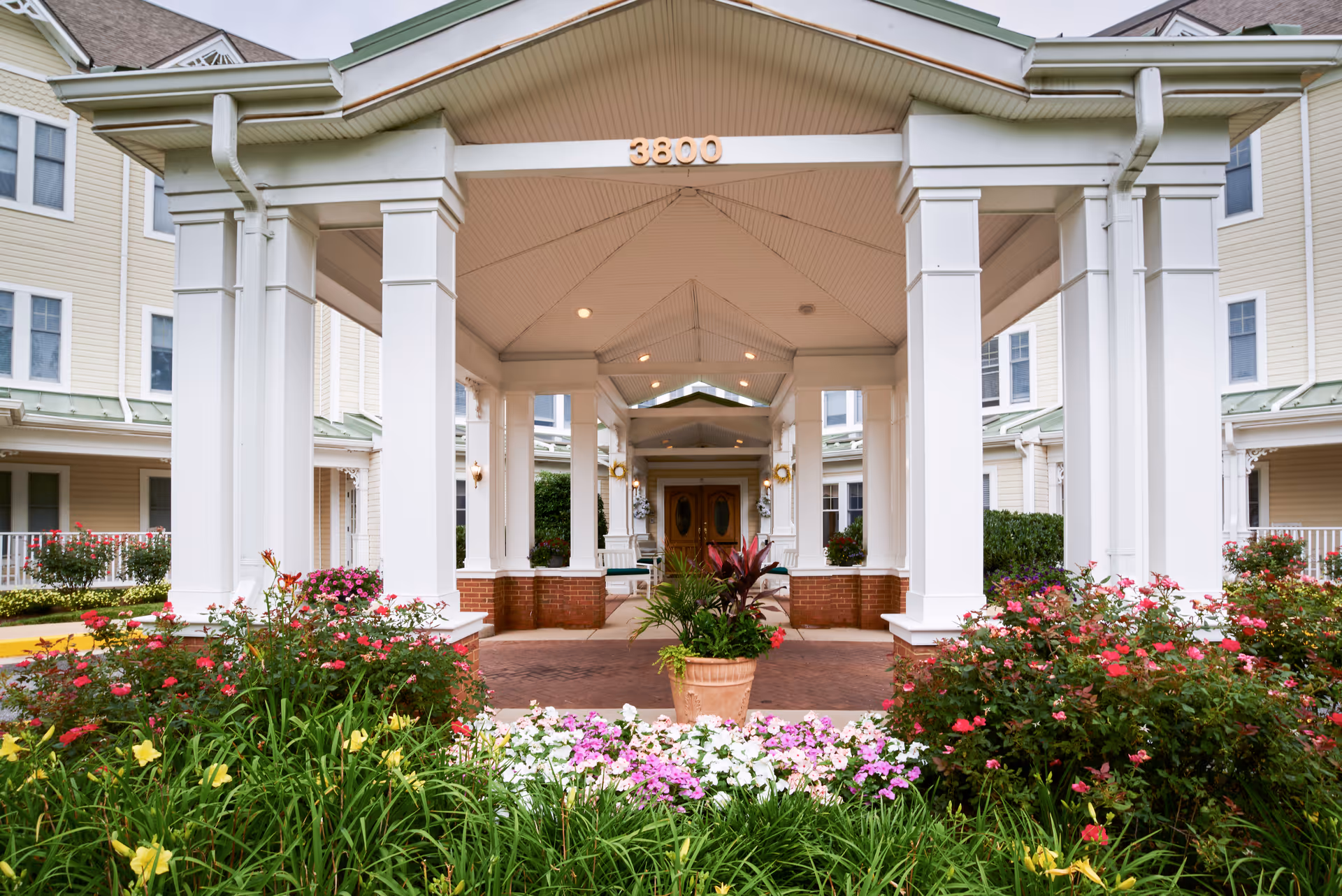 Sunrise of Pikesville front entrance with white columns and colorful flowers.