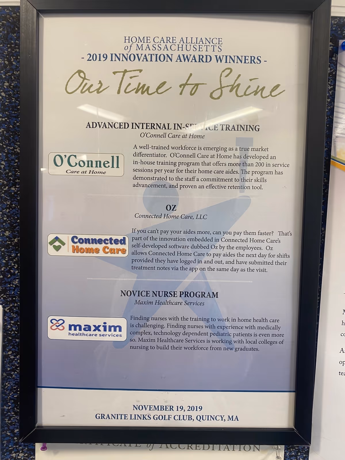 Framed poster highlighting 'Our Time to Shine' along with awards, mounted in a hallway.
