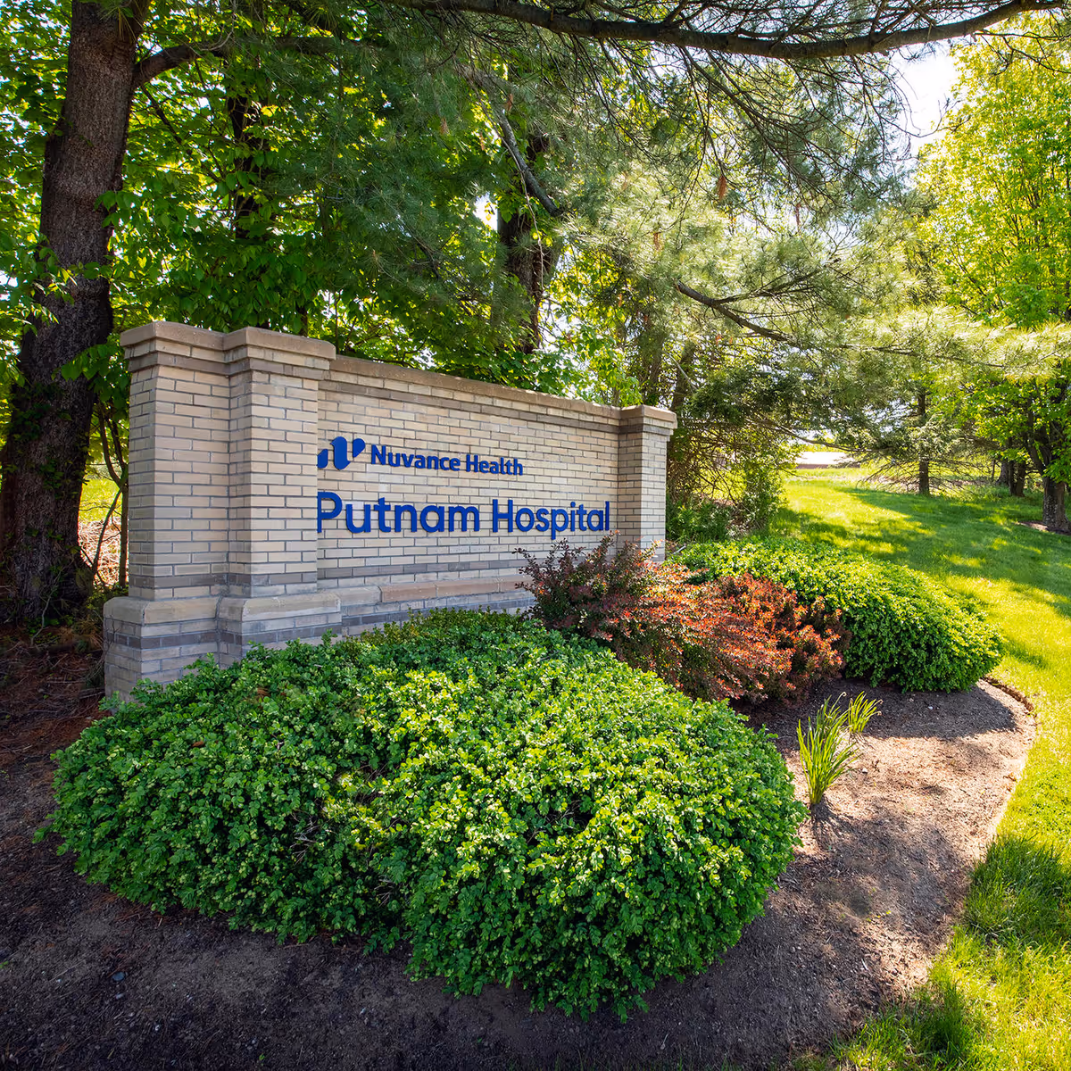 Brick sign reads Nuvance Health Putnam Hospital amid trees and landscaping.