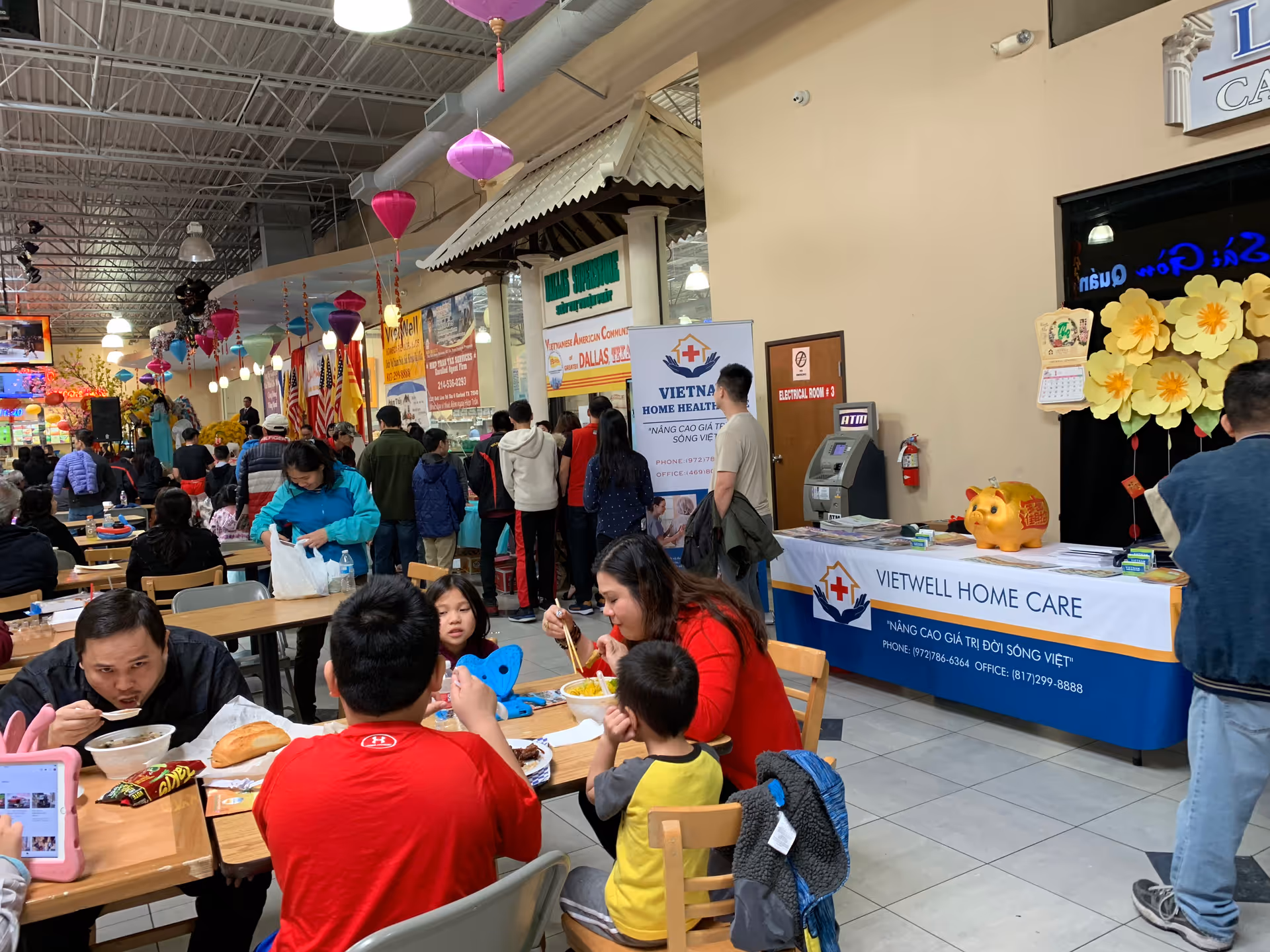 Indoor dining area at a Vietnamese health care event with banners and people eating.