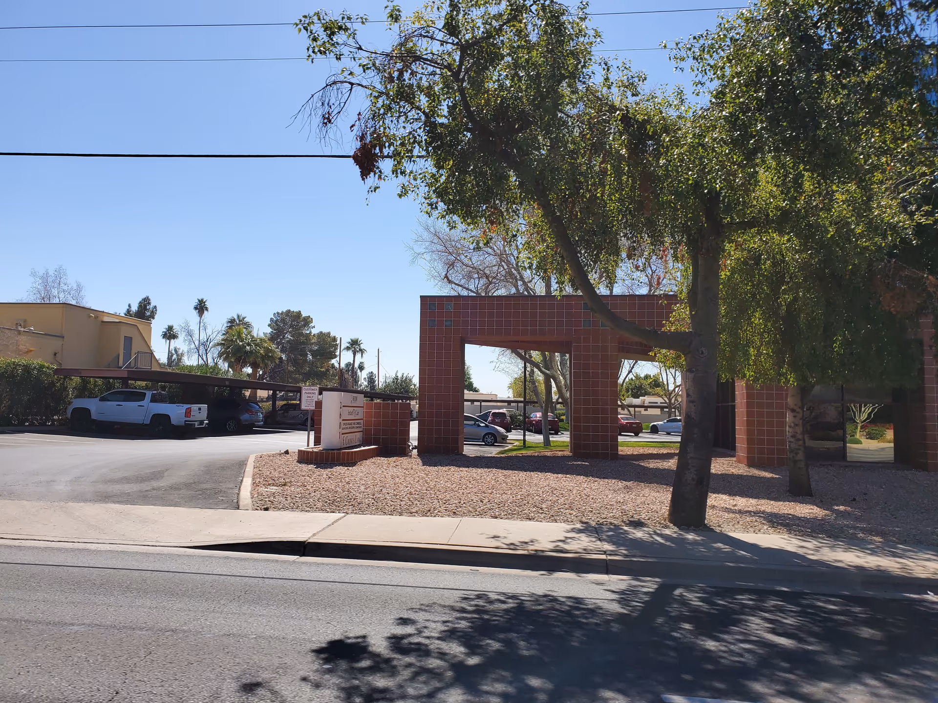 Street view of an exterior building entrance with a red tiled arch and parked cars.
