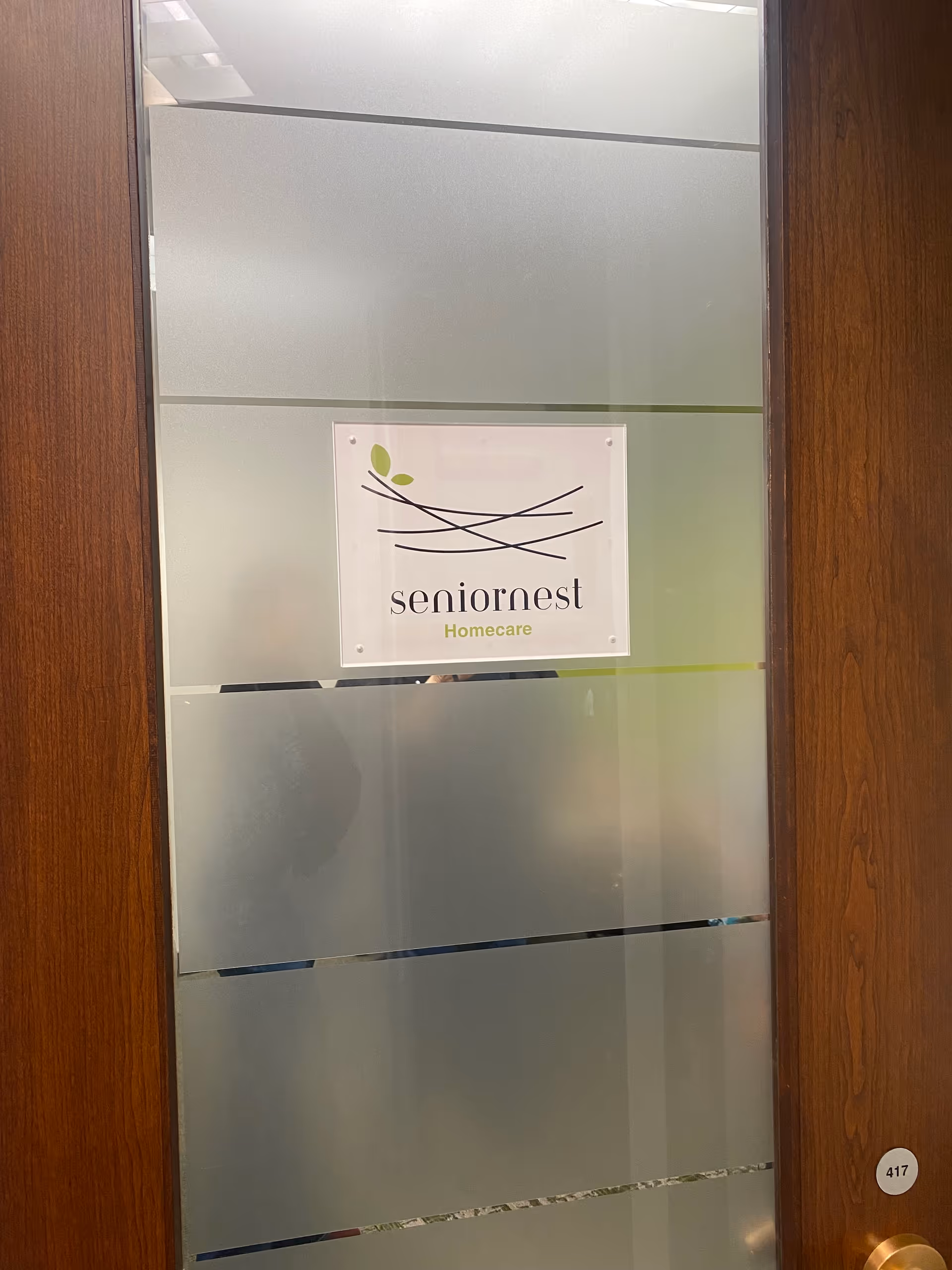 Frosted glass door with Seniornest Homecare sign and wooden frame inside.
